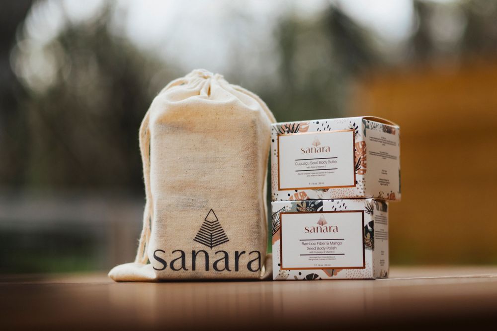 Sanara branded cloth bag and skincare product boxes arranged on wooden surface.
