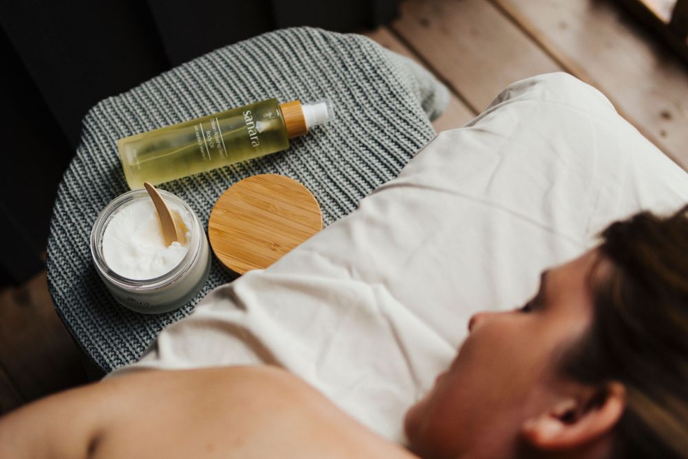 Spa products including oil and cream jar arranged on gray textured surface.