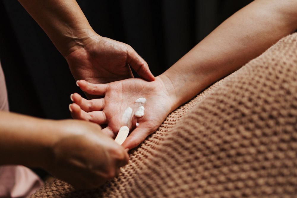 Hands applying massage therapy treatment on textured fabric surface.