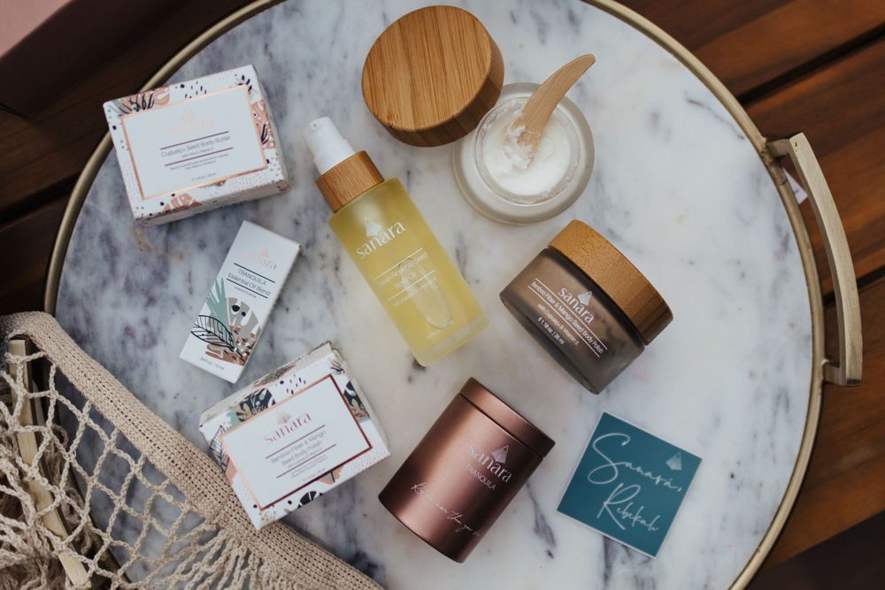 Beauty and skincare products arranged on a marble tray with wooden accents.
