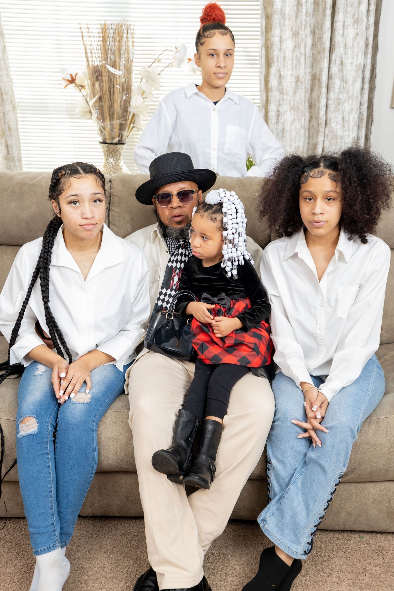 Family portrait on couch featuring coordinated outfits with white shirts and denim.