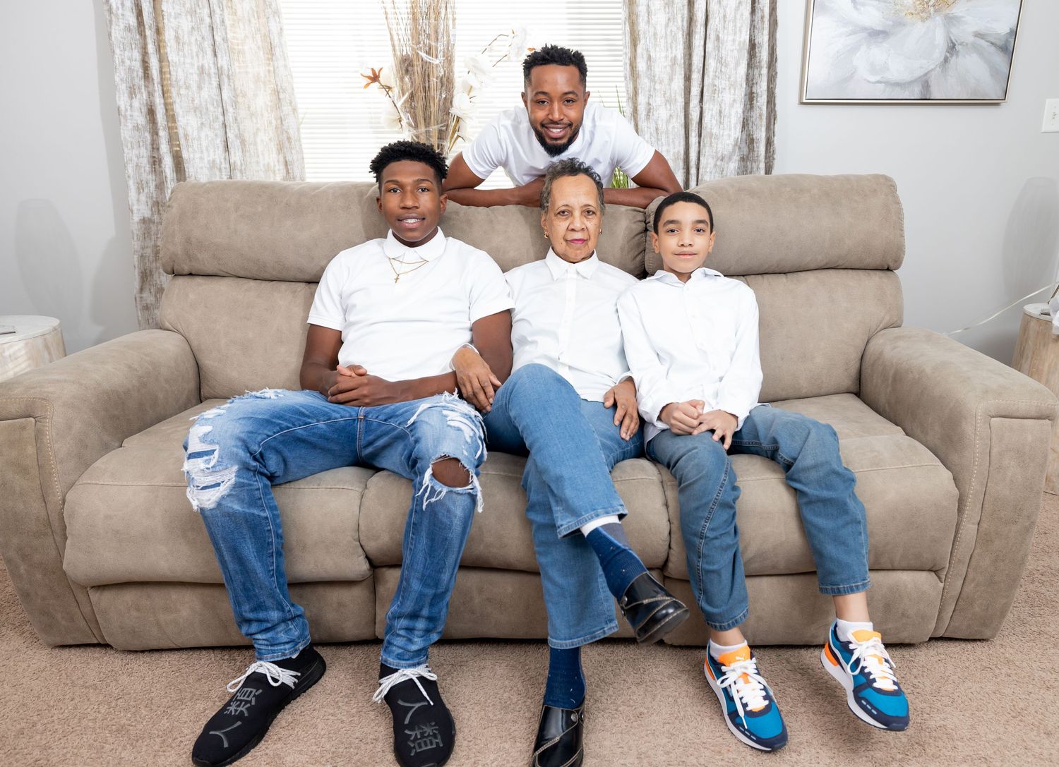 Family members pose together on a gray sofa wearing coordinated casual outfits.
