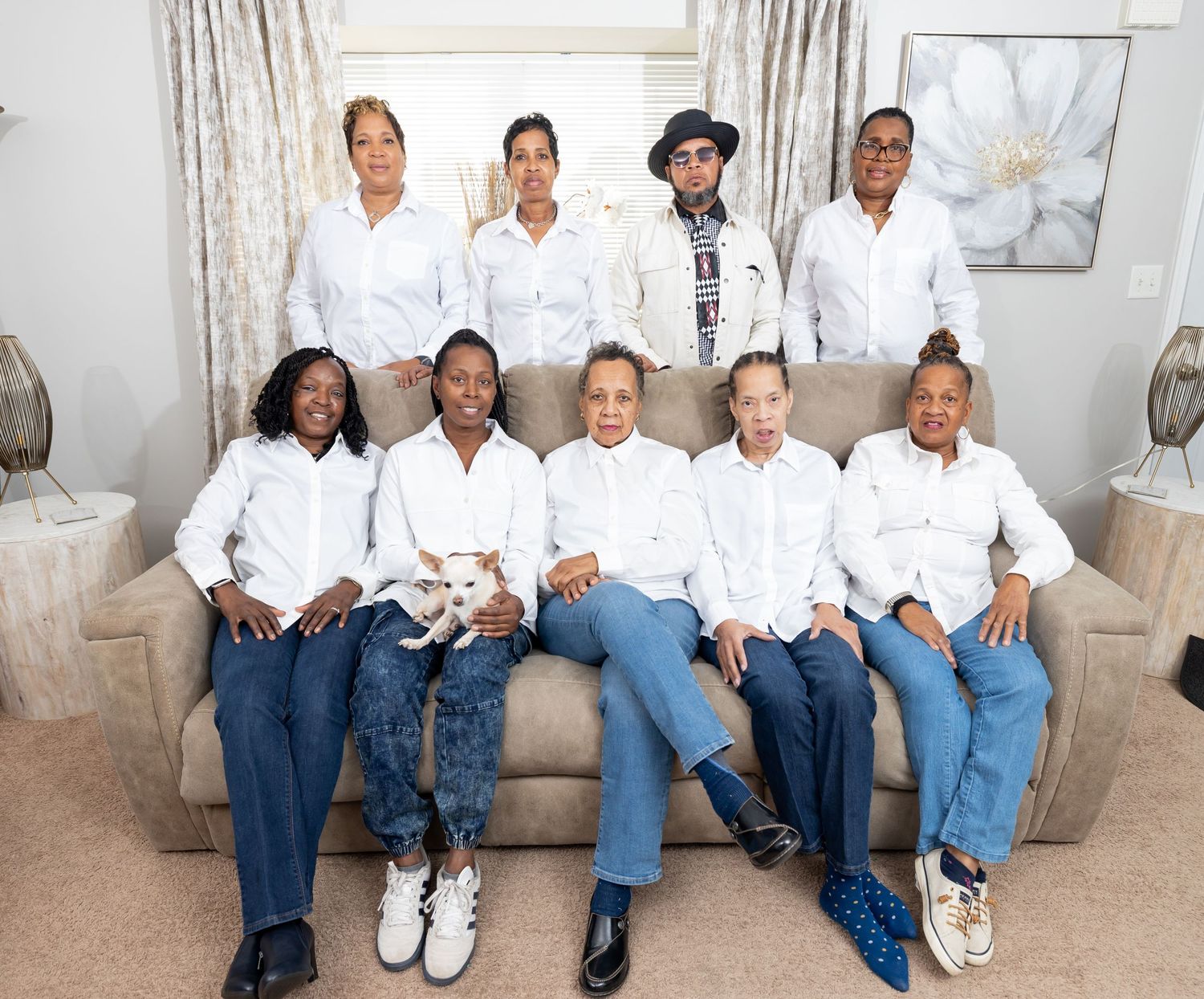 Group photo of people in coordinated white tops and jeans sitting together on a beige sofa.