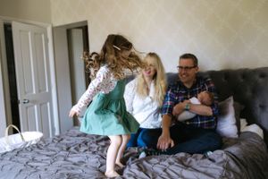 Candid family moment on a bed showing playful interaction and laughter.
