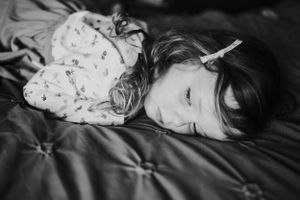 Black and white portrait of a child sleeping peacefully on textured bedding.