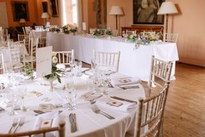 Elegant wedding reception table setup with white linens, chiavari chairs, and delicate floral centerpieces.