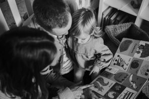Family gathered together looking at photo album in black and white.