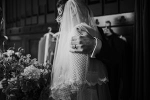 Artistic black and white photograph capturing delicate lacework details of a wedding veil.