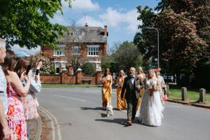 Wedding party walking down a suburban street with colorful houses in the background.