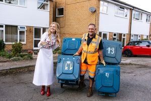 A fun wedding photo with a waste collection worker and blue bins on a residential street.