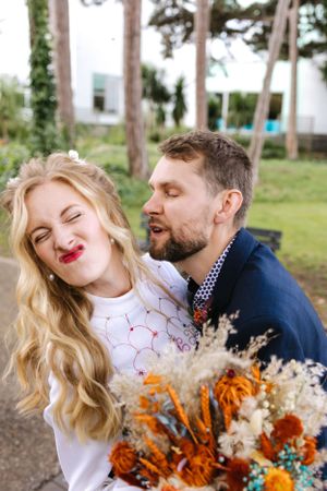 A joyful moment captured outdoors with a beautiful orange and white dried flower bouquet.
