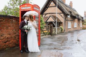 Newlyweds share an intimate moment in a classic red British phone booth.