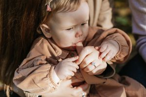 Close-up of small child's hands being held during intimate family moment outdoors.