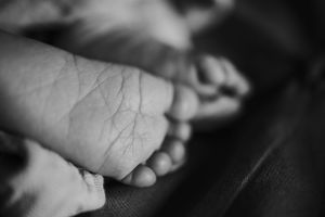 Black and white close-up of a baby's tiny foot showing delicate skin texture.