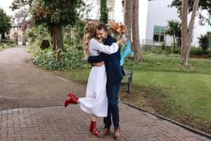 A romantic embrace on a brick pathway surrounded by greenery.