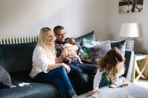 A family shares a tender moment together on their grey couch.