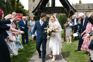 Wedding party showering newlyweds with confetti as they exit the church ceremony.