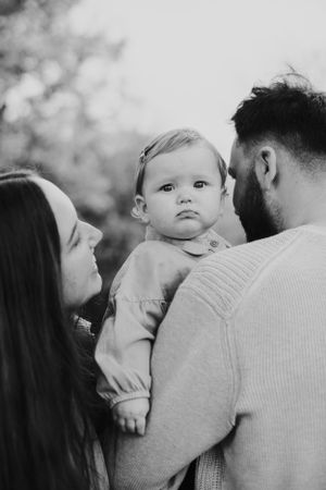 Black and white intimate family portrait capturing tender moment with infant.