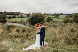 A newly married couple shares an intimate moment in a field of tall grass on their wedding day.