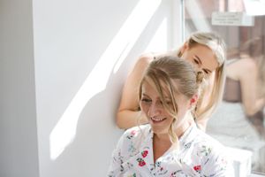 Two people sharing joyful moment in bright sunlit room.