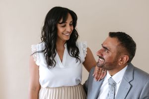 Casual couple sharing a tender moment in white room.