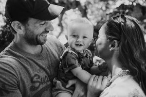 Black and white photo of a joyful family moment with a laughing baby.