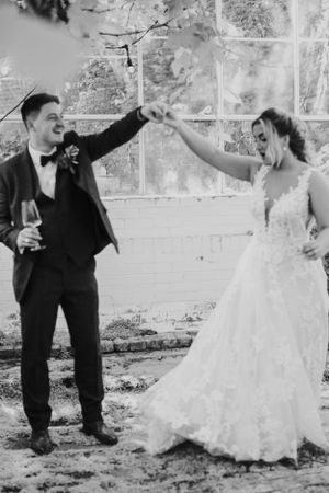 Newlyweds in formal attire sharing a celebratory dance move.