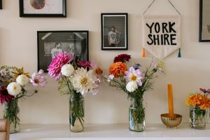 Multiple flower arrangements displayed on a shelf with a Yorkshire banner and framed artwork.