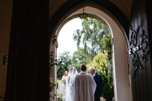 Wedding ceremony exit through a grand archway framed by lush garden greenery.