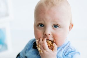 Small child in blue shirt enjoying messy snack time.