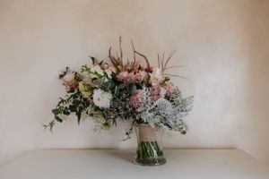 Elegant floral arrangement with white and pink blooms in clear glass vase.