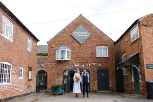 A couple stands outside a traditional brick building entrance.