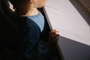 Artistic silhouette of person in blue clothing by window.