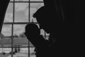 Black and white intimate family portrait with newborn in casual home setting.