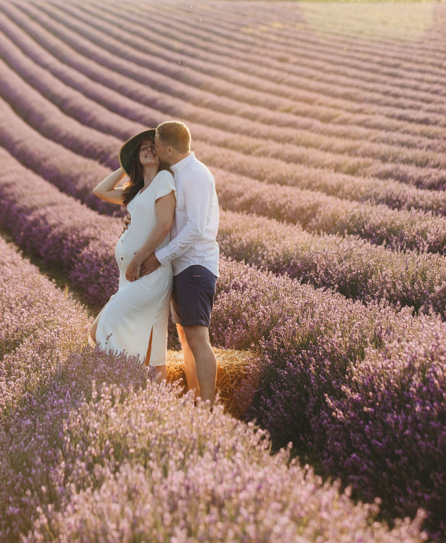 Couple sharing intimate moment in lavender field during golden sunset.