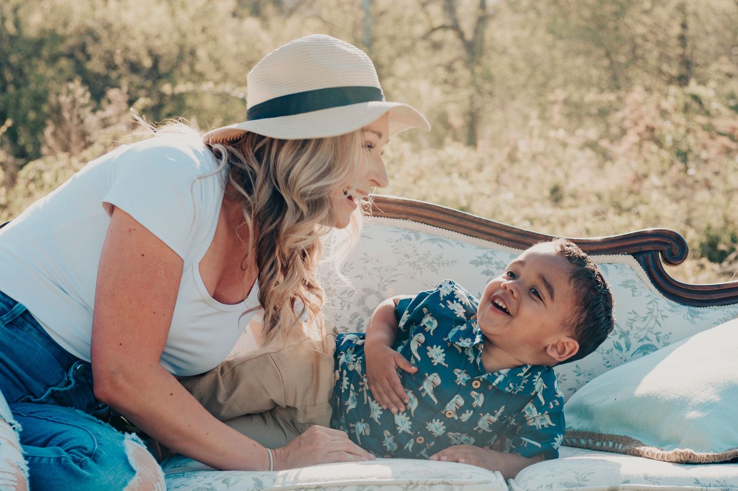 Candid romantic outdoor scene with a sun hat and floral fabric in warm sunlit setting.