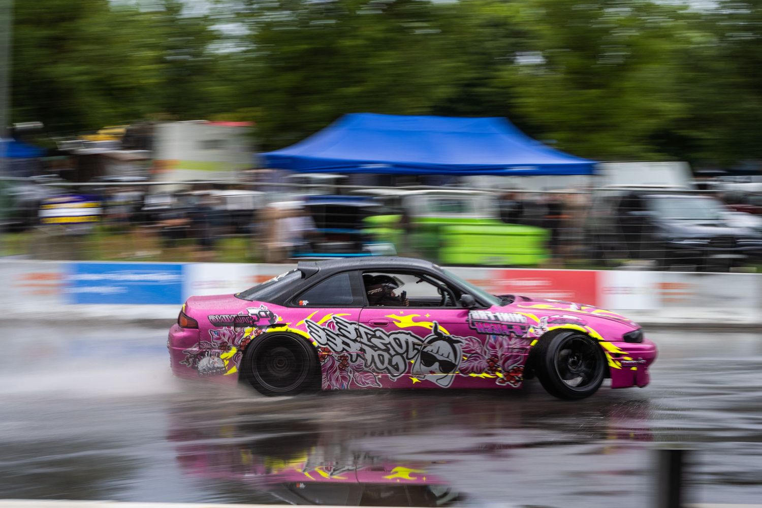 Pink drift car sliding through wet track with motion blur effect.