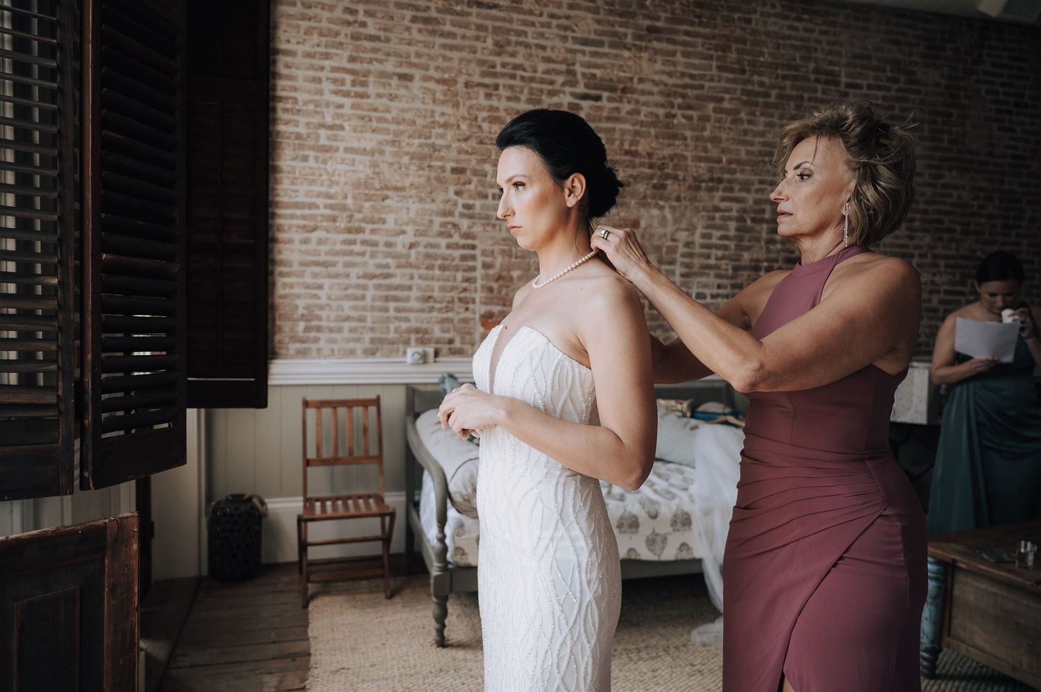 Final wedding preparations in a rustic brick-walled room with vintage furniture.
