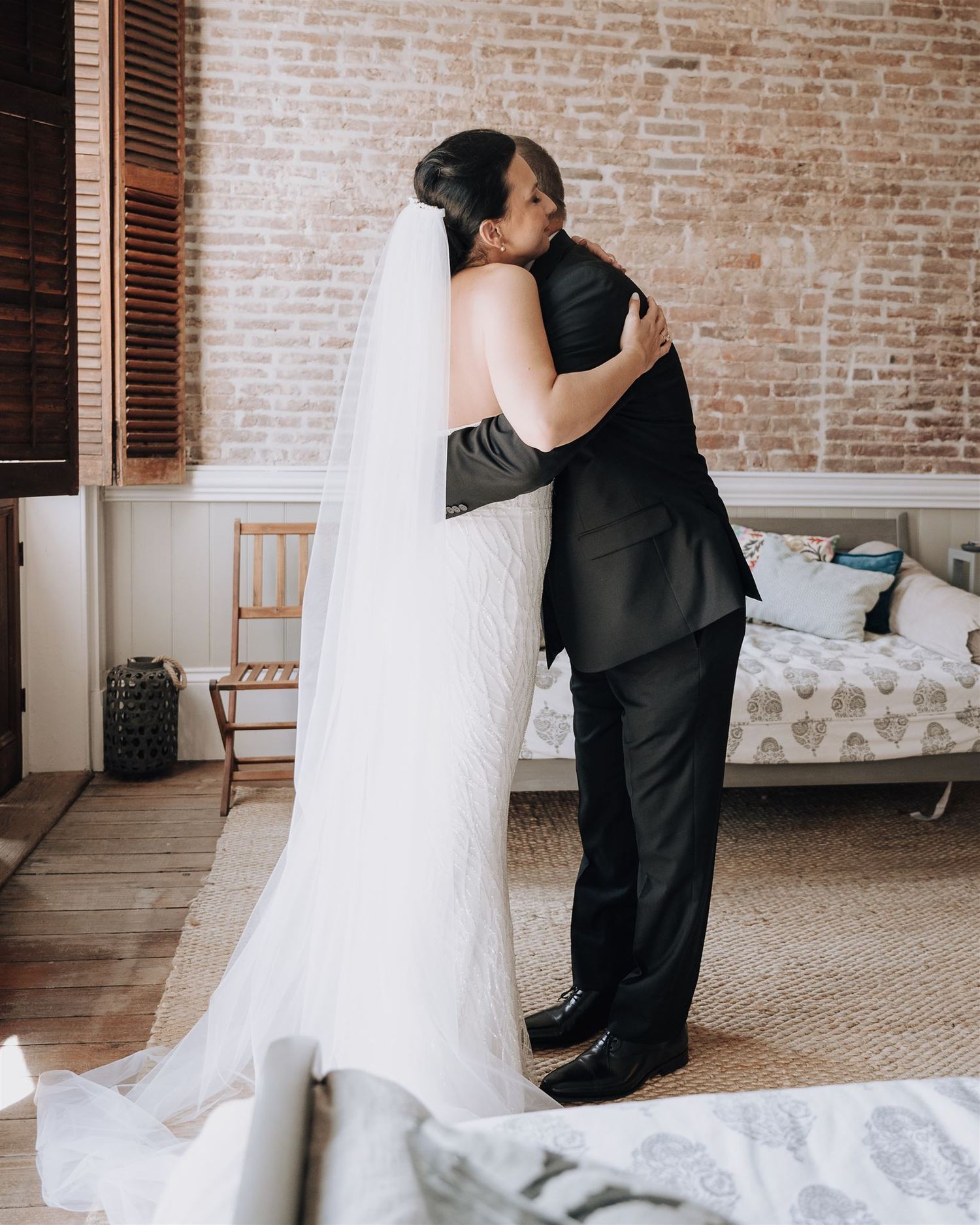 A touching first look moment between newlyweds in front of an exposed brick wall.