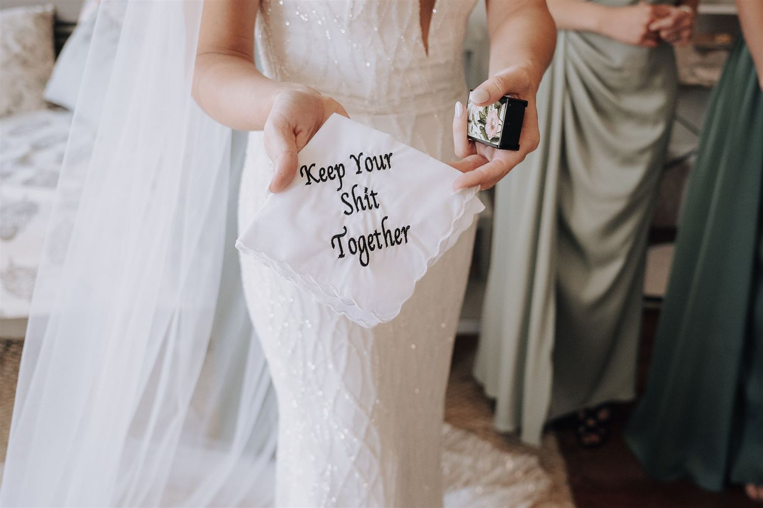 Close-up of embroidered wedding handkerchief reading 'Keep Your Shit Together' held by bride.