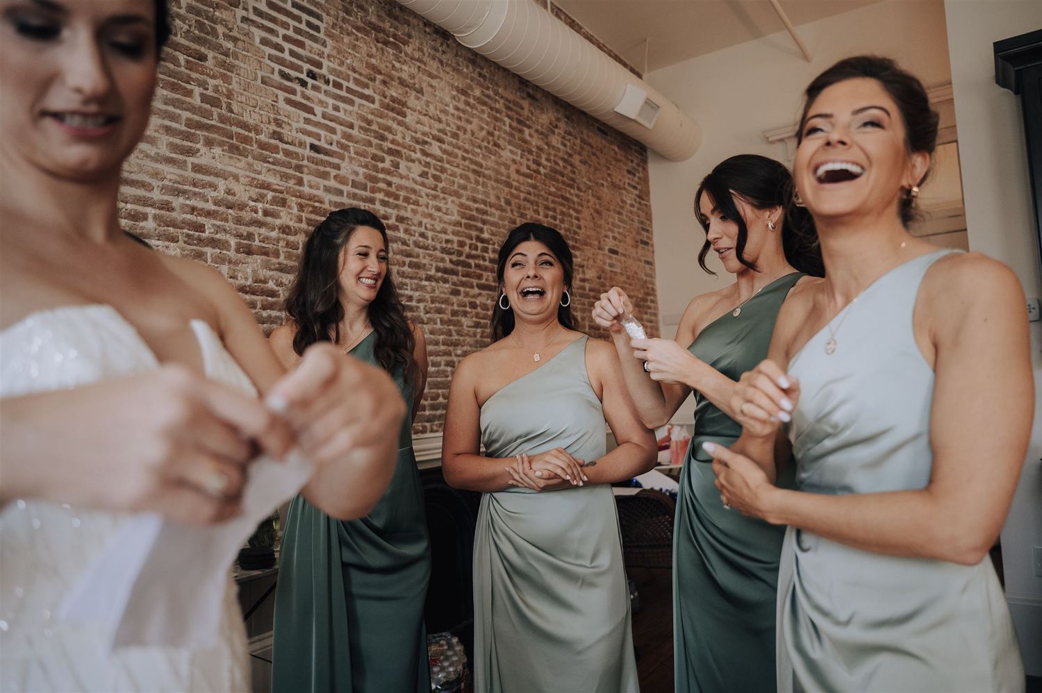 Candid moment of wedding party laughing together during pre-ceremony preparations.