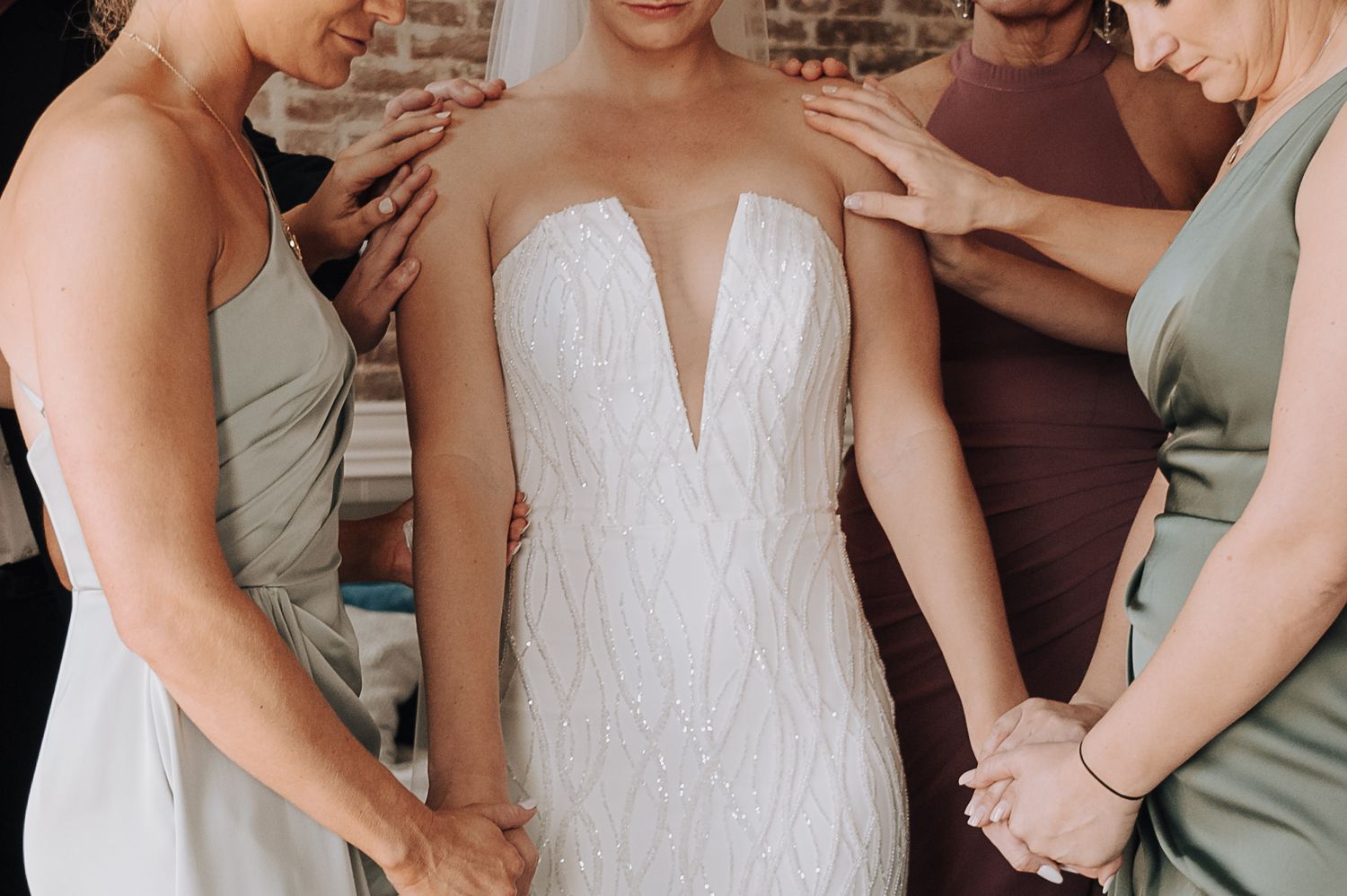 Detail shot of wedding dress with bridesmaids helping adjust the gown.