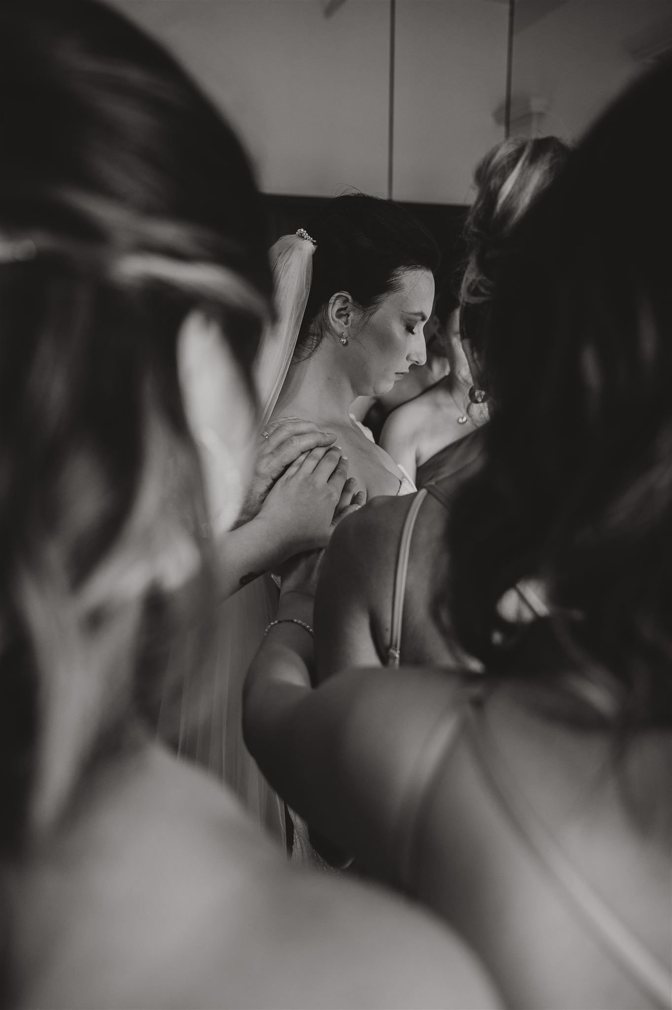 Artistic black and white photo of wedding preparation with soft focus and candid emotions.