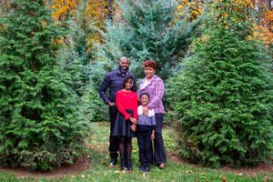 A family poses together among evergreen trees during autumn.