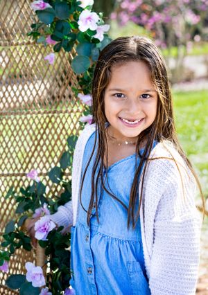 Spring portrait session featuring a child in blue and white clothing near blooming flowers.