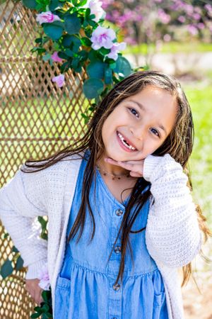Playful portraits of a child in blue and white clothing against a floral garden backdrop.