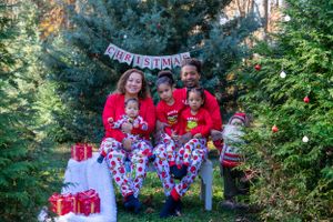 Family holiday photo setup with Christmas decorations and wrapped presents in an outdoor setting.