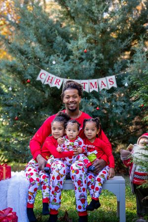 Holiday family photo with matching Christmas pajamas and festive decorations outdoors.