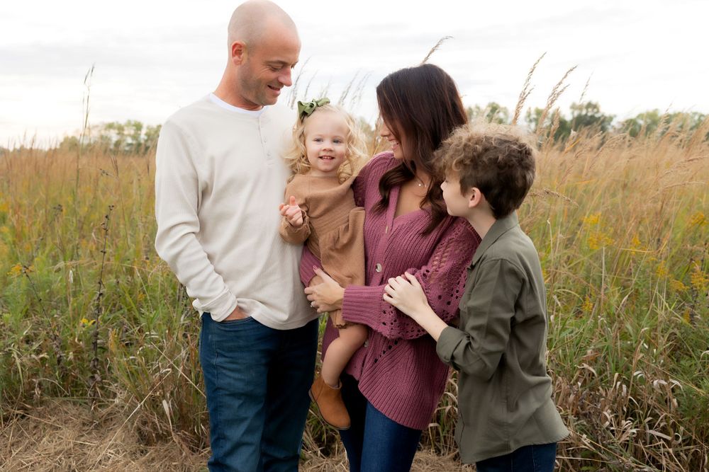 Happy family shares a candid moment together in a field of tall grass.