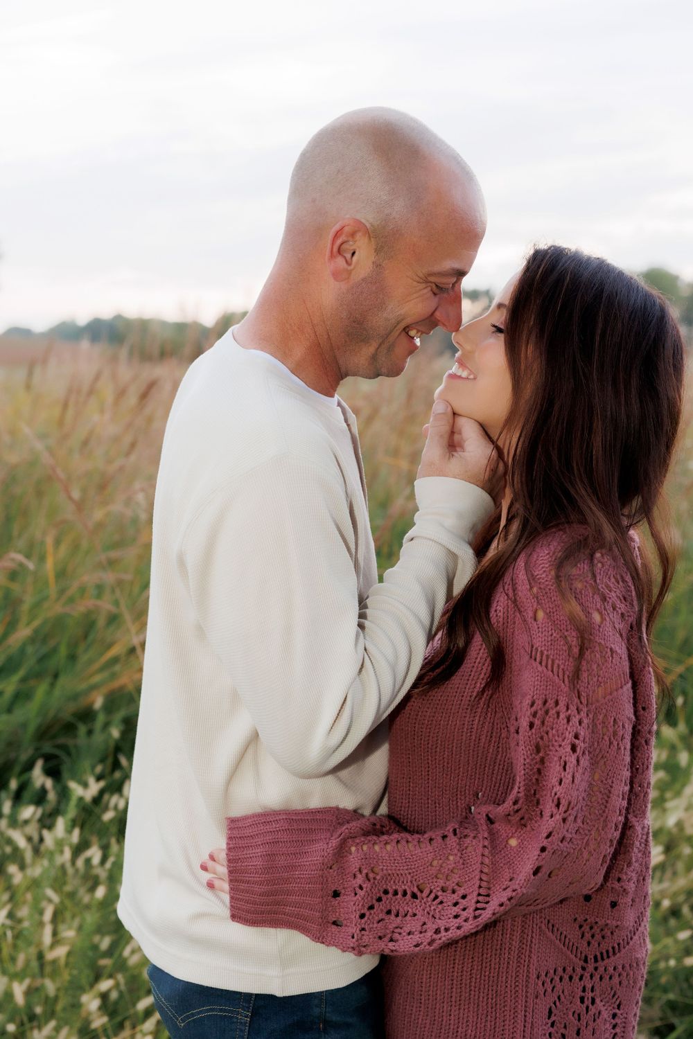 Couple sharing intimate moment together in field during sunset.